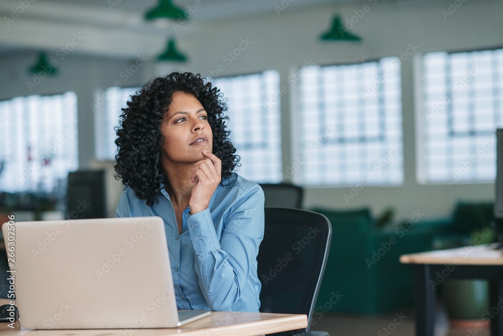 Young businesswoman thinking while using a laptop at work